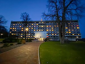 Krankenhausgebäude in der Dämmerung mit beleuchtetem Weihnachtsbaum auf dem Dach
