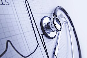 Ein Stethoskop, das auf einem medizinischen Diagramm mit grafischen Linien im Hintergrund ruht.