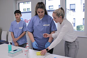 Boys und Girls DAy IMG_8614 Eine Frau in hält eine Spritze in der Hand und erklärt einem Jungen und einem Mädchen etwas.